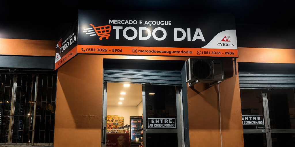 Fachada do Mercado e Açougue Todo Dia iluminada à noite